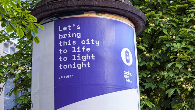 Detailansicht der Infosäule auf dem Kronenplatz, groß im Bild das Zitat der Band Refused »Let’s bring this city to life to light tonight«